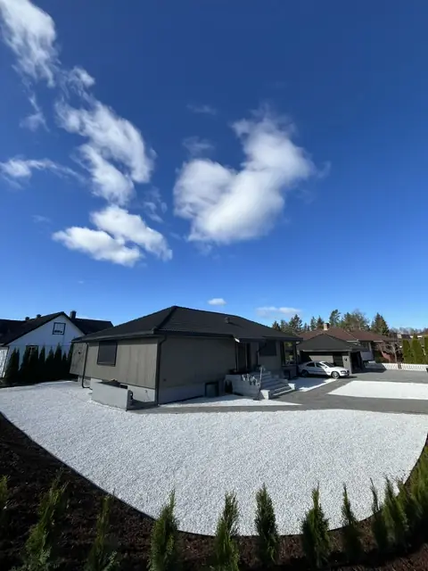 Ferdig plass med hvit grus og ny hekk foran et hus