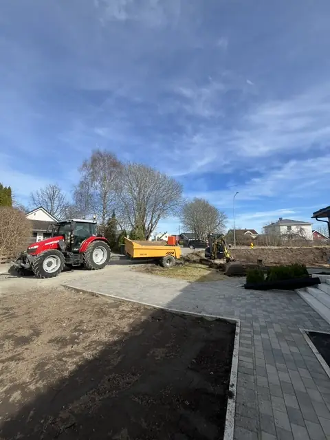 Traktor og tilhenger ved ny belegningsstein og et jordbed